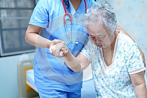 Asian nurse physiotherapist doctor care, help and support senior or elderly old lady woman patient get up from bed at hospital war