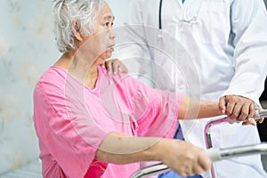 Asian nurse physiotherapist doctor care, help and support senior or elderly old lady woman patient walk with walker at hospital