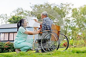 Asian nurse sit to take care near senior man sit on wheelchair and draw or paint for relax and revive good health of old people in