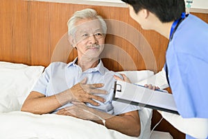 Asian nurse taking care of an elderly man lying on patient bed at  senior healthcare center