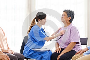 Asian nurse using a stethoscope for checking the heart rate of the senior female patient at home. Medical assistance . Caregiver