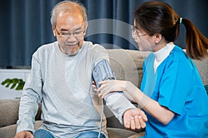 Asian nurse visit patient senior man at home she measuring arterial blood pressure on arm