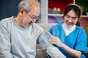 Asian nurse visit patient senior man at home she measuring arterial blood pressure on arm