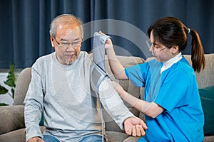 Asian nurse visit patient senior man at home she measuring arterial blood pressure on arm