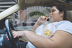 Asian obese woman eating during driving a car