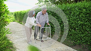 Asian old couple walk with walker at  home. senior man using a walker  working with elder woman in the park . mature husband and