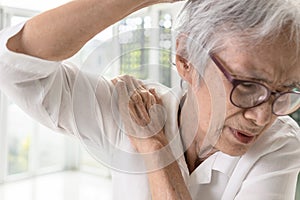 Asian old elderly woman with shoulder bone pain,stiffness and painful when raising her upper arm,suffers difficulty in lifting or