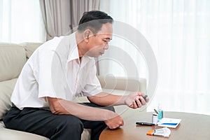 Asian old man check a sugar level in his blood by him self