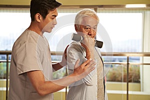 Asian old man exercising using dumbbell in rehab center