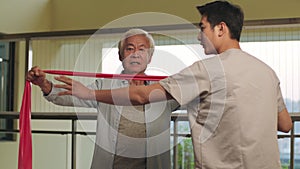 Asian old man exercising using resistance band in rehab center