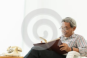 Asian Old man glasses professor sitting on the chair reading textbook