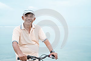 Asian old man riding his bike at the beach