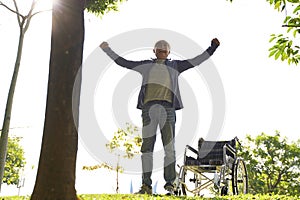 Asian old man standing by wheel chair with joy