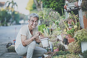 Asian old man taking care of houseplant at home garden