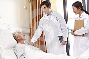 Asian old man talking to doctors in hospital ward