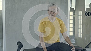 Asian old man tired after effort exercise in the gym, asia senior sweat sitting expression exhausted and breathing after workout