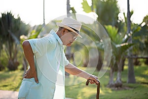 Asian old man walking in park and having a back pain, backache. Senior healthcare concept