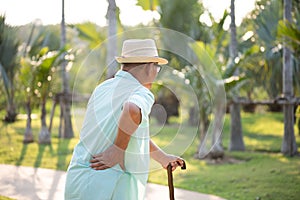 Asian old man walking in park and having a back pain, backache. Senior healthcare concept