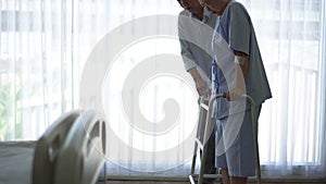 Asian old senior couple husband help wife doing physical theraphy walking with walker to recover from injury love and care