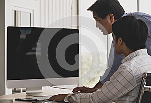 Asian old senior male father stand and young handsome teen son sit use index finger pointing blank empty black computer monitor