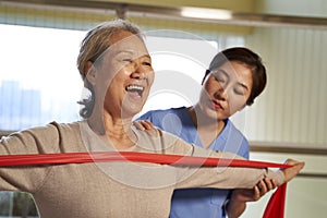 Asian old woman exercising using resistance band in rehab center
