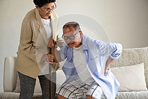 Asian old woman helping an elderly man having a back pain, backache at home. Senior healthcare concept