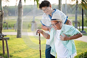 Asian old woman helping an elderly man having having a pain on heart, heart attack in a park. Senior healthcare concept