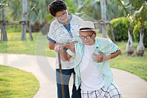 Asian old woman helping an elderly man having having a pain on heart, heart attack in a park. Senior healthcare concept
