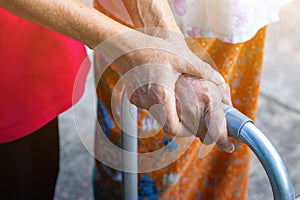 Asian old woman standing with her hands on a walker with daughter& x27;s hand,Hand of old woman holding a staff cane for helping