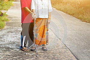 Asian old woman standing with her hands on a walker with daughter& x27;s hand,Hand of old woman holding a staff cane for helping