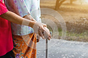 Asian old woman standing with her hands on a walker with daughter& x27;s hand,Hand of old woman holding a staff cane for helping