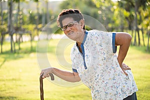 Asian old woman walking in park and having a back pain, backache. Senior healthcare concept