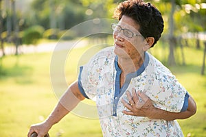 Asian old woman walking in park and having a with pain on heart, heart attack. Senior healthcare concept