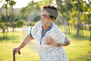 Asian old woman walking in park and having a with pain on heart, heart attack. Senior healthcare concept