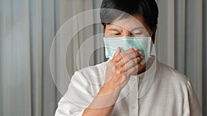 Asian old woman wearing a face mask indoor coughing