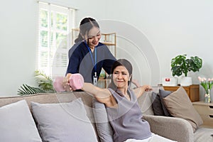 Asian older woman doing physiotherapist with support from nurse or caregiver. Senior elderly woman using dumbbells