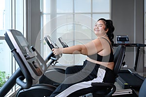 Asian overweight women exercising on the exercise bike in indoor fitness club. Healthy and Fitness concept. Weight loss workout, h