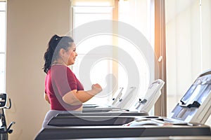 Asian overweight women in sportswear running on treadmill in fitness club. Weight loss workout, healthy lifestyle concept