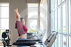 Asian overweight women in sportswear running on treadmill in fitness club. Weight loss workout, healthy lifestyle concept