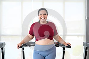 Asian overweight women in sportswear running on treadmill in fitness club. Weight loss workout, healthy lifestyle concept. Look at