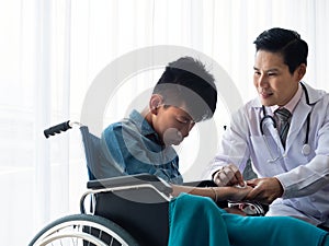 Asian Paediatrician man clean and sterilize back hand area of disabled child who sitting on wheelchair by organic cotton wool