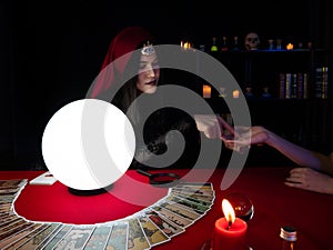 Asian palmist woman reading line on hand fate and spread tarot cards for client choose one from the set