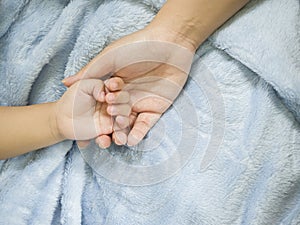 Asian parent hands holding newborn baby fingers, Close up mother's hand holding their new born baby