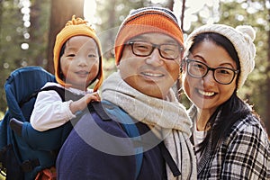 Asian parents carrying toddler daughter in forest, close up