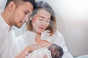 Asian parents with newborn baby being breastfeeding, Close up portrait of asian young couple father mother holding new born baby.