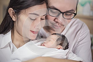 Close up portrait of asian young couple holding their new born baby.