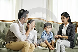 Asian parents and two children chatting at home