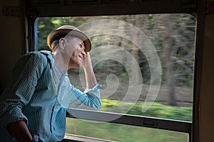 Asian passenger wearing hat looking out of train window photo