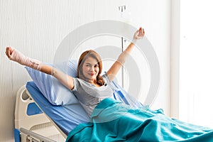 Asian patient woman lying at hospital bed with saline sign for cheerful. Drop of saline solution to help patient