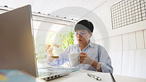 Asian people 30s drinking coffee and relaxing after looking  new trading  platforms stock tickers or graphs ,economics worker at